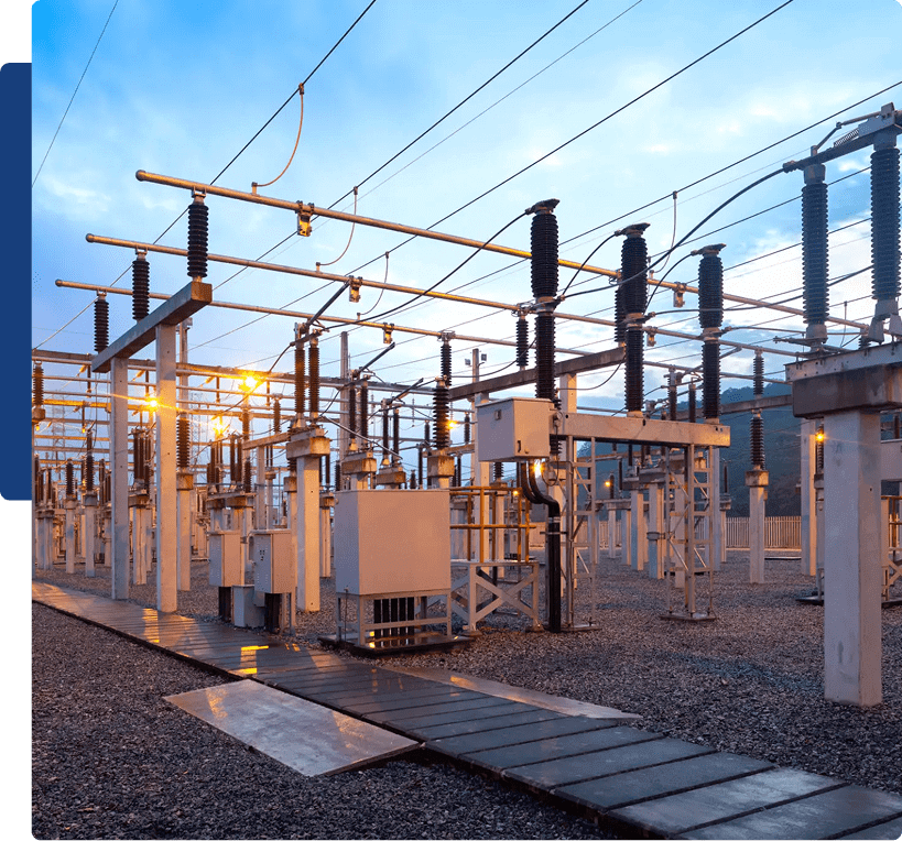 Electrical substation with transformers and power lines at sunset.