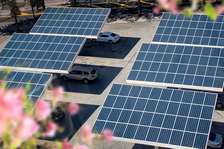 Solar panels providing shade to parked cars in a parking lot.