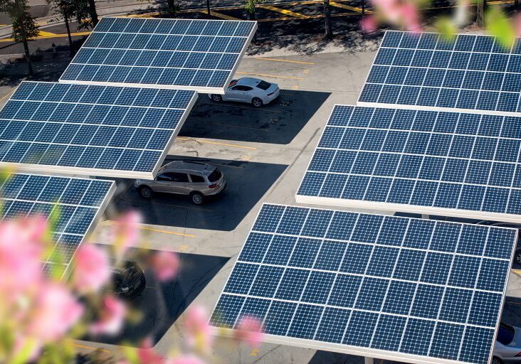 Solar panels providing shade to parked cars in a parking lot.
